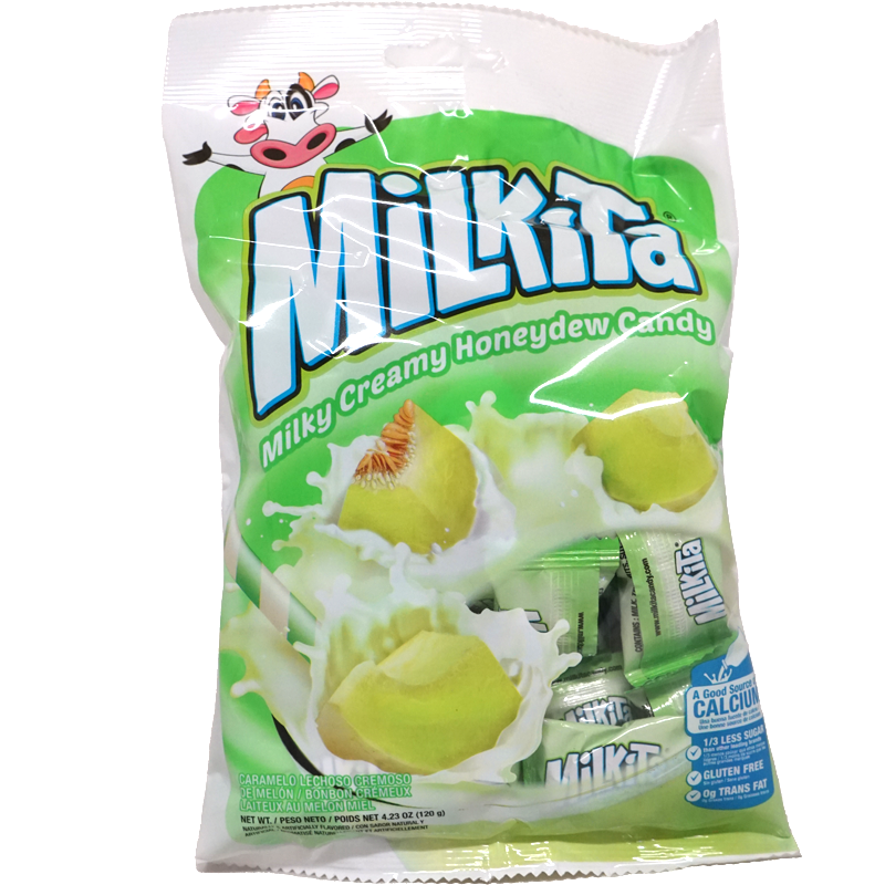 Front view of package. The packaging features a playful cow mascot at the top, adding a touch of fun. The main visual element is a vibrant image of honeydew melon pieces immersed in creamy milk, evoking the rich and refreshing taste of the candy. The background is a fresh green, complementing the honeydew theme and making the product visually appealing. The bottom highlights important features like being a good source of calcium, gluten-free, and containing no trans fat.