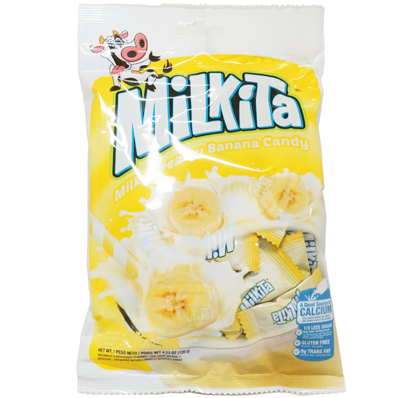 Front view of package. The package features vibrant images of sliced bananas and splashes of creamy milk, emphasizing the luscious, milky banana flavor of the candy. A cheerful cartoon cow is depicted on the top left, adding a playful touch. The candies are individually wrapped, and some are visible through the clear window at the bottom of the package, inviting consumers to reach in and enjoy the sweet treats inside.