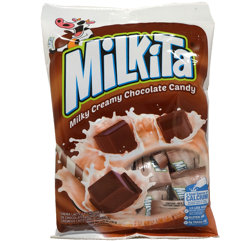 Front view of package. The package features an inviting design with splashes of milk surrounding luscious chocolate squares, hinting at the creamy delight inside. A playful cartoon cow adds a touch of fun, making it appealing for both kids and adults.