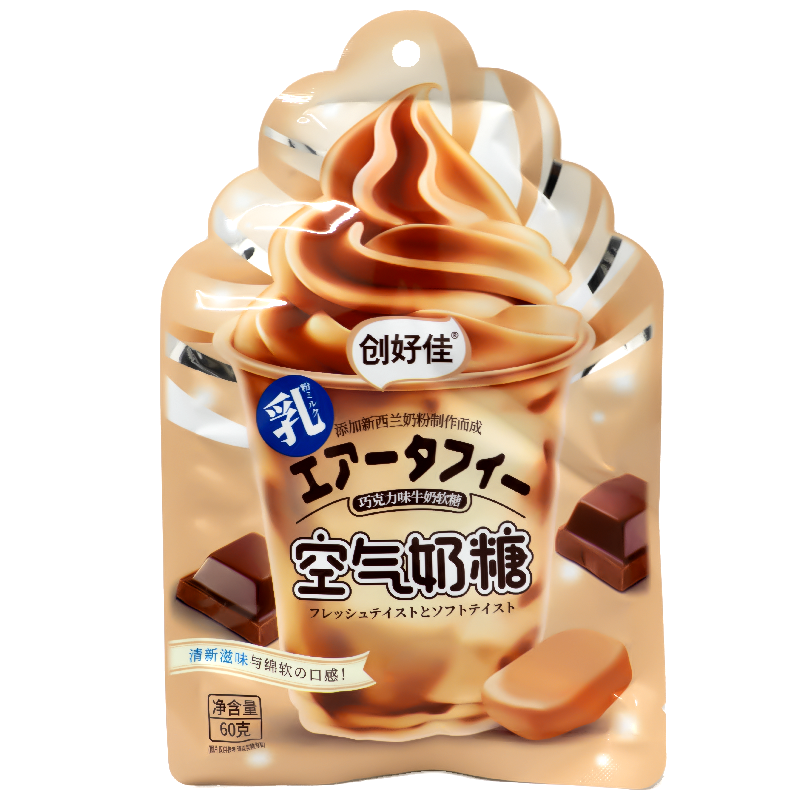 The package features an image of a luscious, swirled chocolate soft serve ice cream, evoking a sense of creamy indulgence. Surrounding the central image are smaller illustrations of chocolate squares and soft candy pieces, hinting at the rich, chocolatey flavor within. The background is a warm, inviting beige color, complemented by silver accents that add a touch of elegance. The overall design is visually appealing and conveys a sense of deliciousness and luxury.